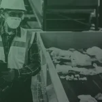 Hazardous waste technician wearing PPE monitoring materials in an industrial setting