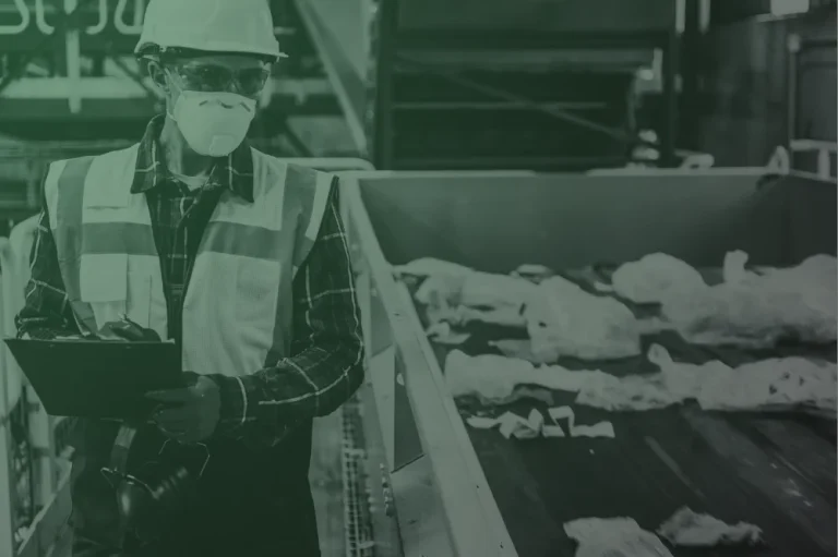 Hazardous waste technician wearing PPE monitoring materials in an industrial setting